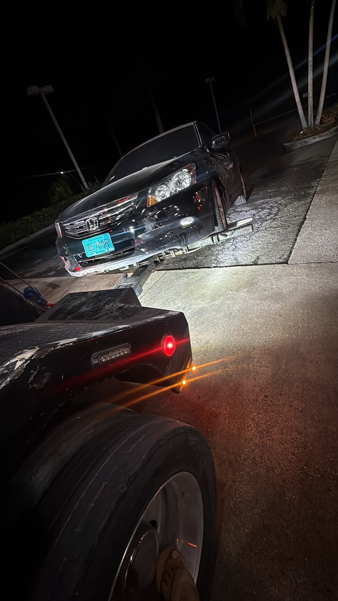 Car loaded on the flatbed at night with the lights on